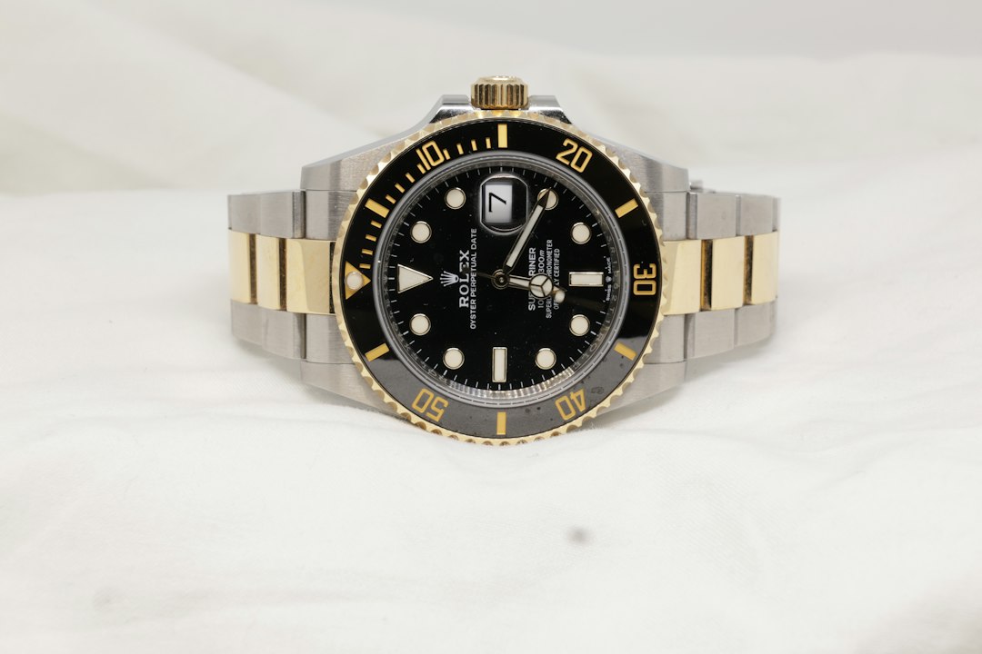 Rolex-Armbanduhr in Schwarz und Gold vor hellem Hintergrund